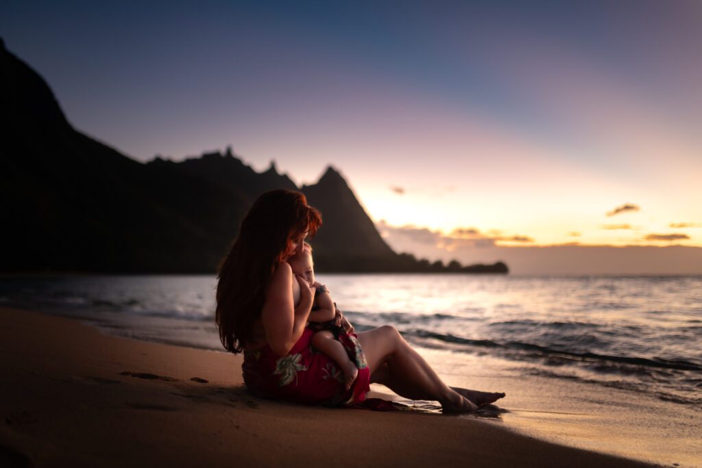 a mom nursing her baby at tunnels beach on kauai 